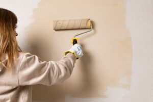 ragazza di spalle con rullo che pittura parete