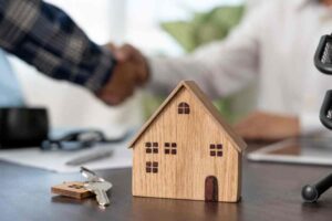 Stretta di mano e casa di legno