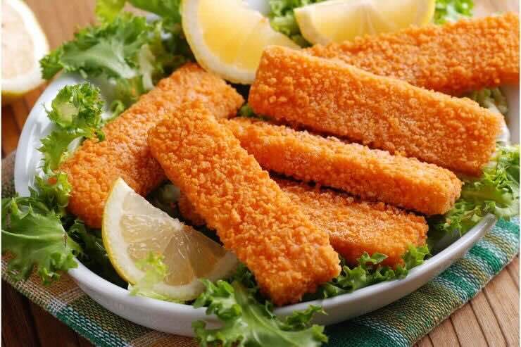 Bastoncini di pesce su letto di insalata e fette di limone